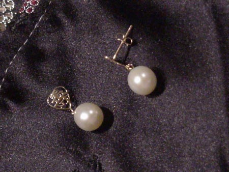 7.5mm by 9mm oval white pearl earrings dangling from a 14K gold heart.